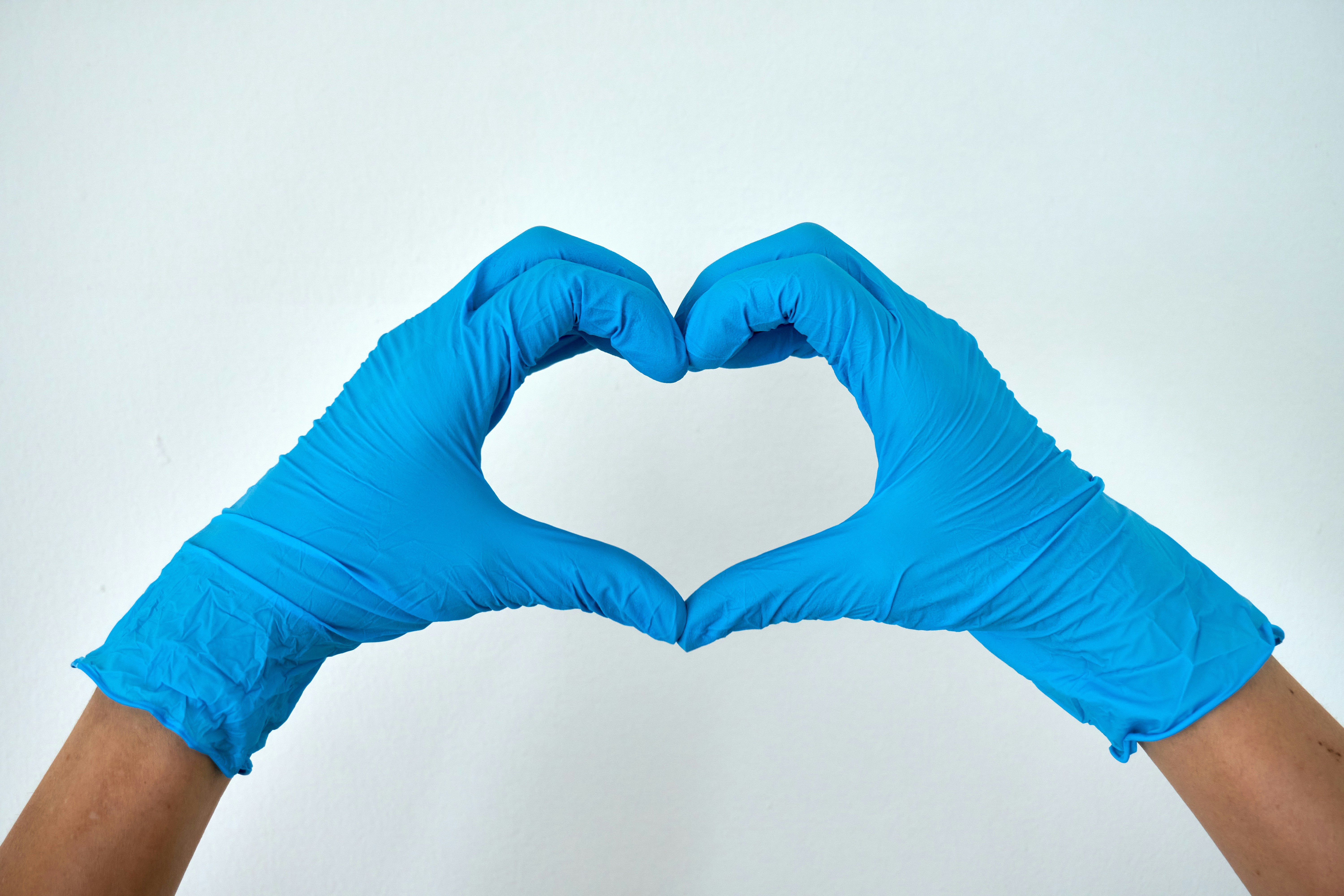 Hands in blue surgical gloves forming a heart shape